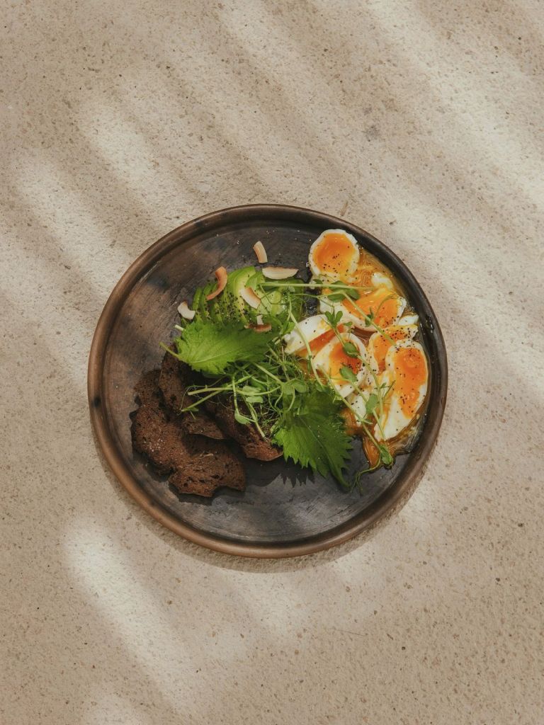 A dark bowl of grilled meat and fresh salad on a stone surface, seen from above